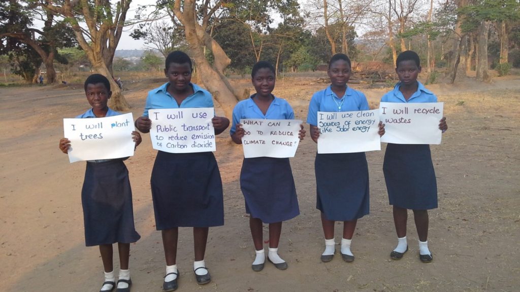 Students at Lilongwe Girls' Secondary School in Malawi hold up signs showing the ways in which they can help to slow global warming (Photo: UNITAR)