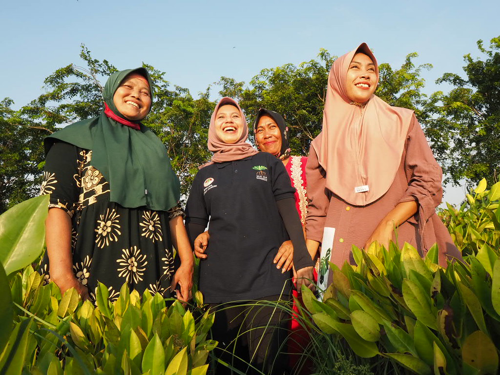 Women from Asia smiling in a field.